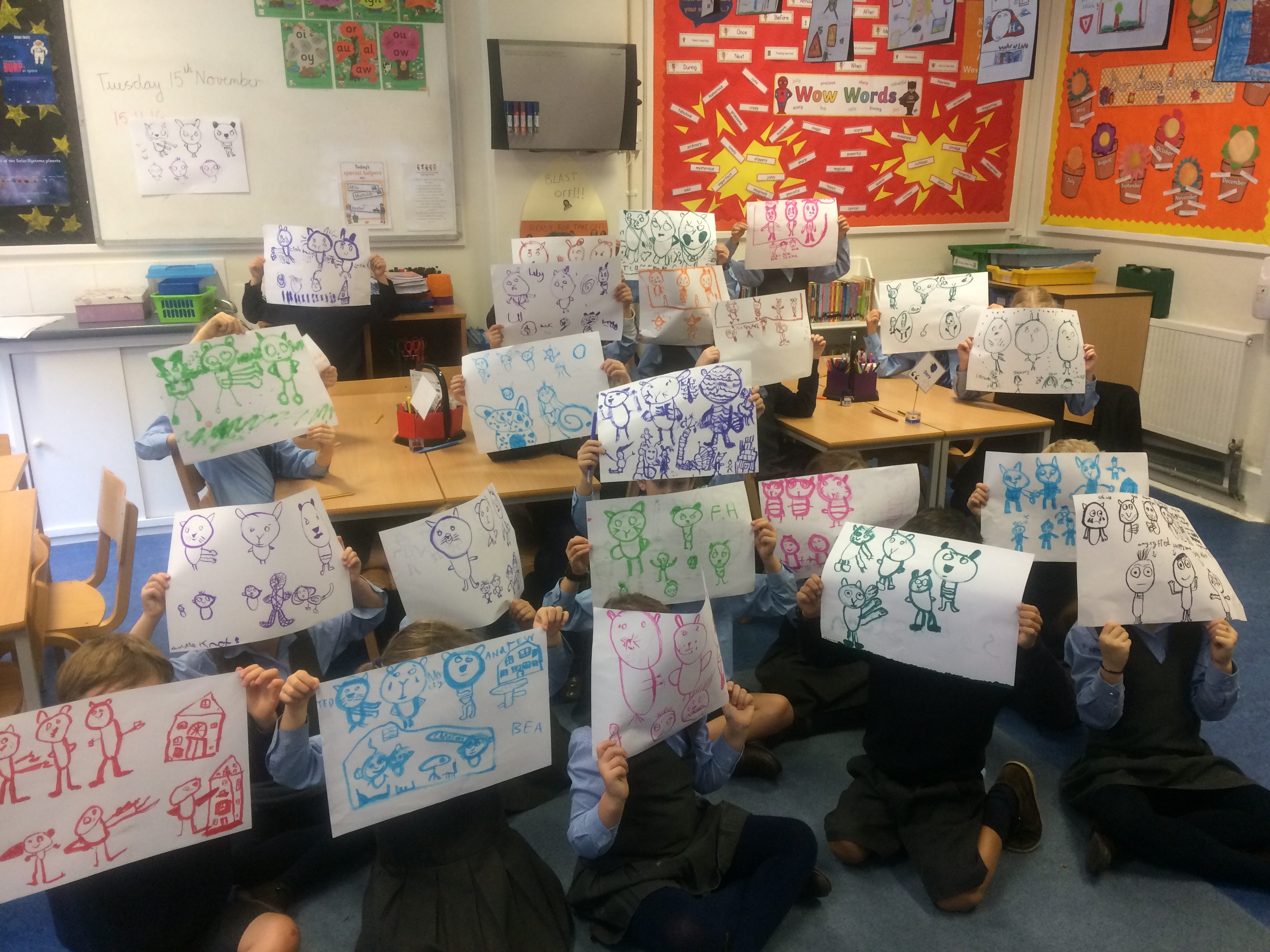 Children in a classroom holding up picture of the characters they have drawn